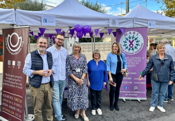 smiling people at MABS special fair stall with purple bunting and balloons 