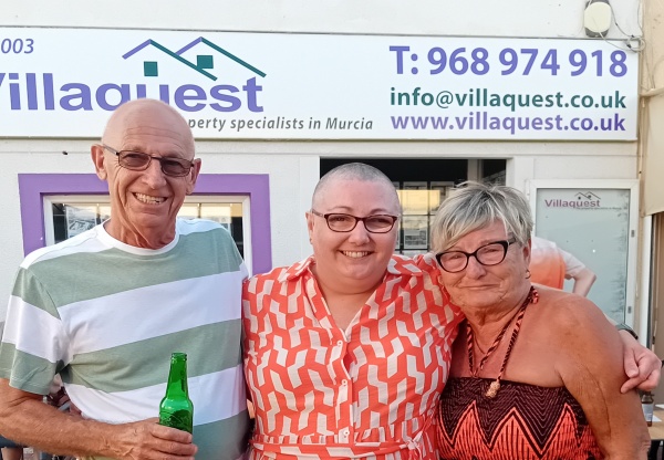 a man and two women with arms around one another, casually dressed and smiling