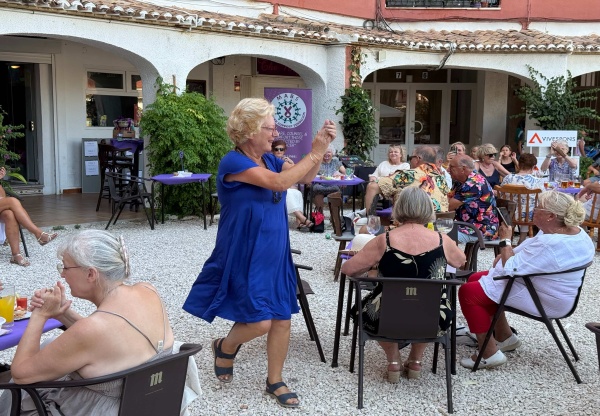 lady in a blue dress clapping while walking amongst people sitting at tables